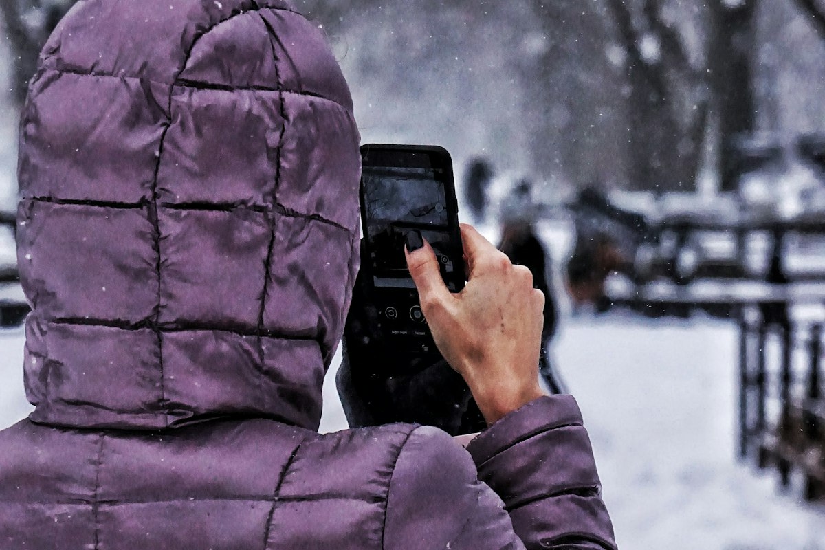 Iemand gebruikt een smartphone buiten in de sneeuw